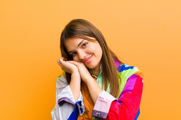 Foto donna sentirsi innamorati e guardare carino, adorabile e felice, sorridendo romanticamente con le mani accanto al viso