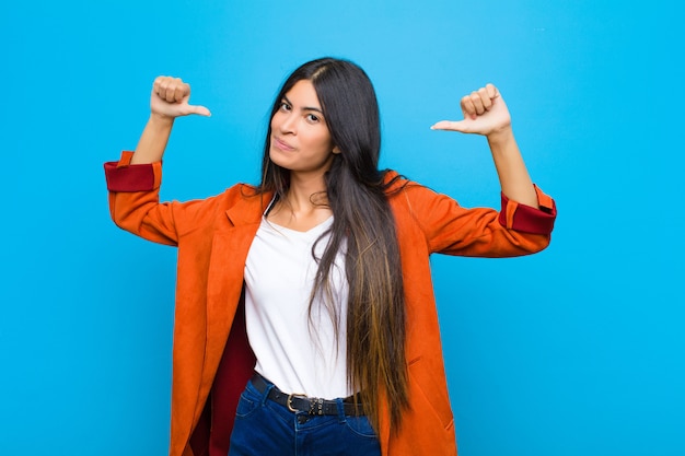 Woman feeling proud, arrogant and confident, looking satisfied and successful, pointing to self