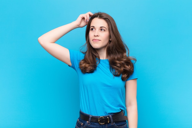 woman feeling puzzled and confused, scratching head and looking to the side