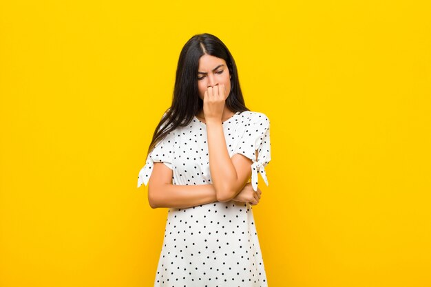 woman feeling serious, thoughtful and concerned, staring sideways with hand pressed against chin