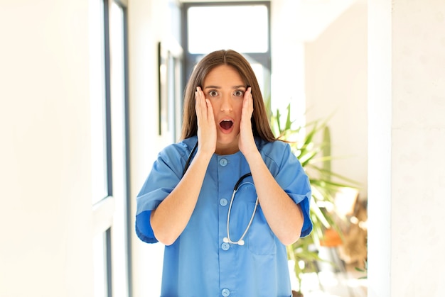 Woman feeling shocked and scared, looking terrified with open mouth and hands on cheeks