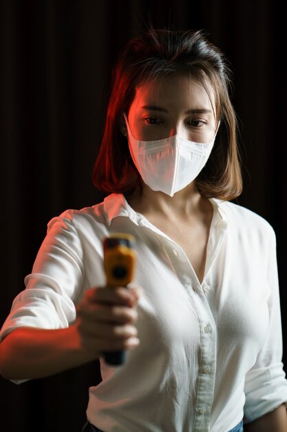 Woman feeling sick wearing protective mask and uses digital thermometer checking temperature