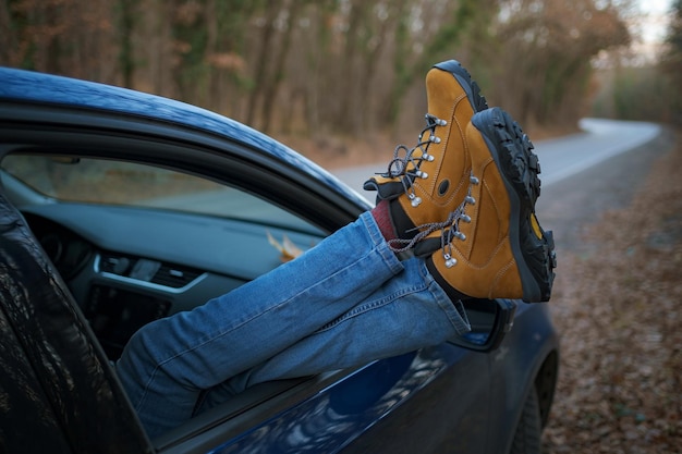 Woman feet on car door feet outside the window at sunset\
forest