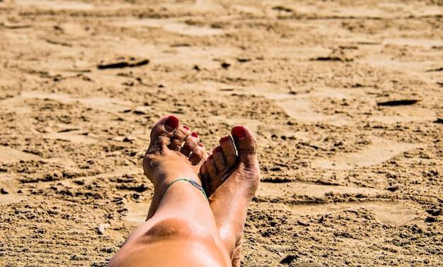 Woman feet in the sand with nails painted red.