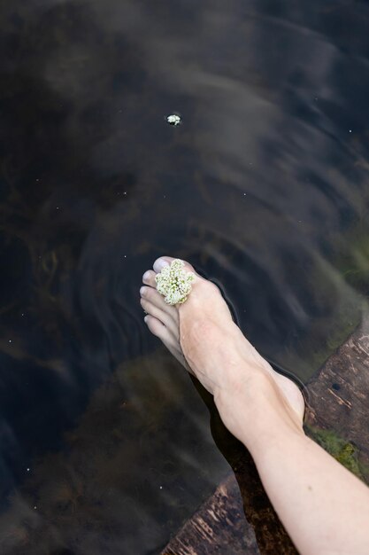 Woman feet slow life and relax on river bark with sunset