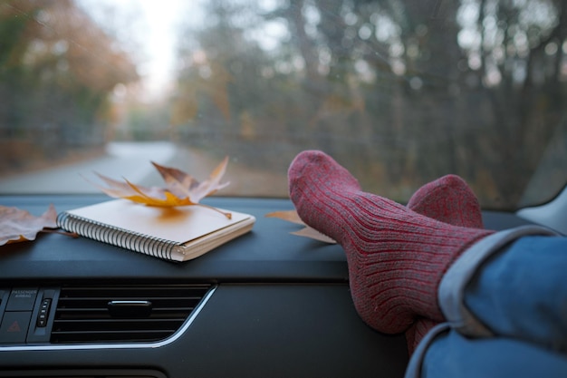 Woman feet in warm socks on car dashboard