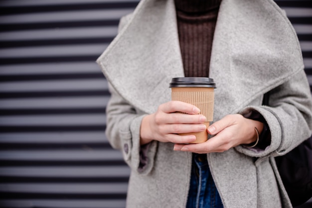 Mano femminile della donna con latte di carta della tazza di caffè.