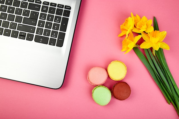 Woman or feminine workspace with notebook, macarons and flowers