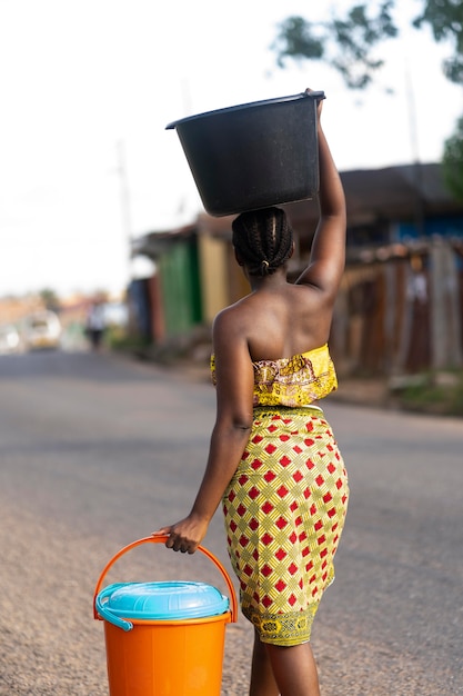 Foto donna che va a prendere l'acqua all'aperto