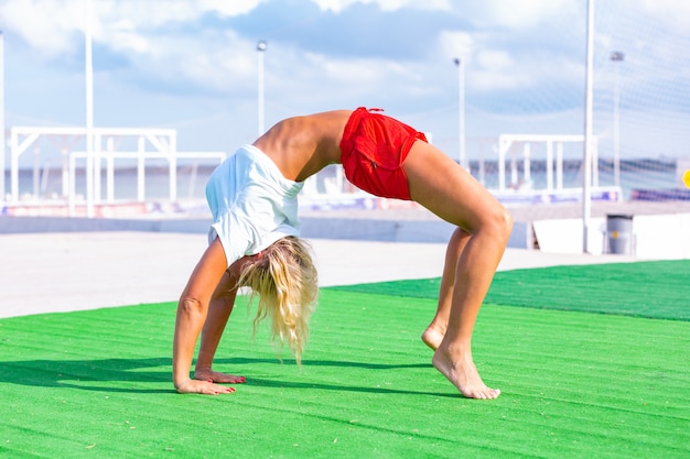 Женщина на поле делая тренировку йоги фитнеса. Элемент Acroyoga для силы и баланса