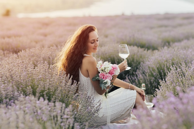 Woman in a field of lavender with a glass of wine