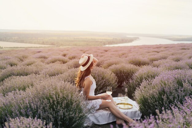 Woman in a field of lavender with a glass of wine