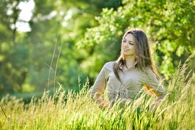 a woman in a field of tall grass with the sun shining behind her