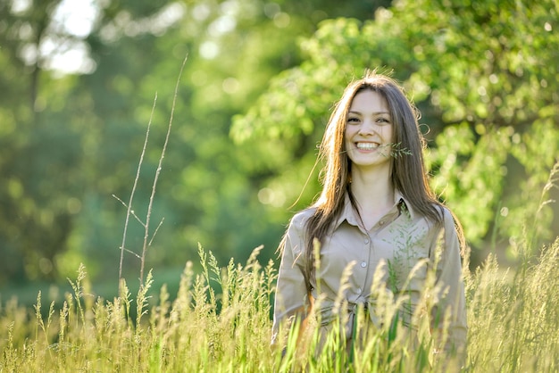 a woman in a field of tall grass with trees in the background