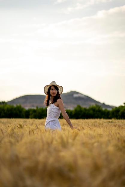 Foto una donna in un campo di grano con una collina sullo sfondo