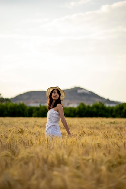 Foto una donna in un campo di grano con una collina sullo sfondo