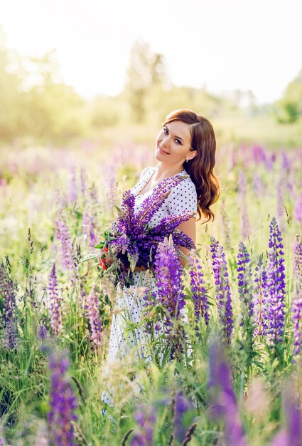 Donna in un campo con un mazzo di fiori selvatici