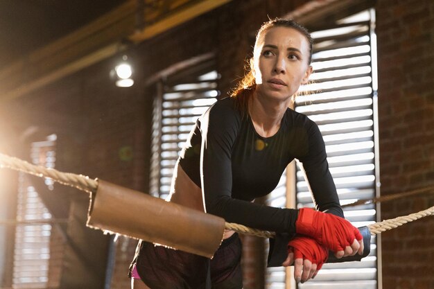 Фото Женщина-боец девушка сила женщина-боец с красным боксом обертывает защитные бинты, стоя на боксе