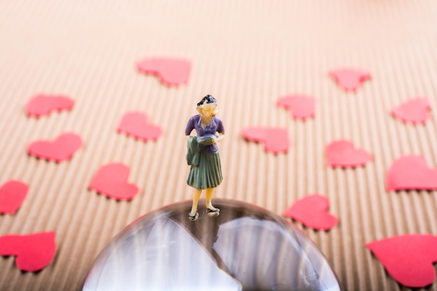 Woman figurine on half a globe with paper hearts