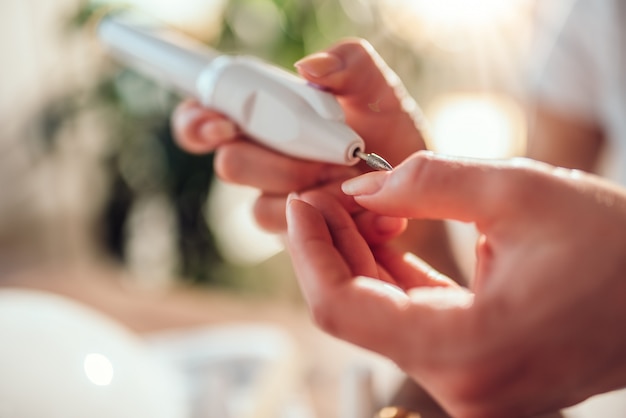 Woman filings nails with electric nail file