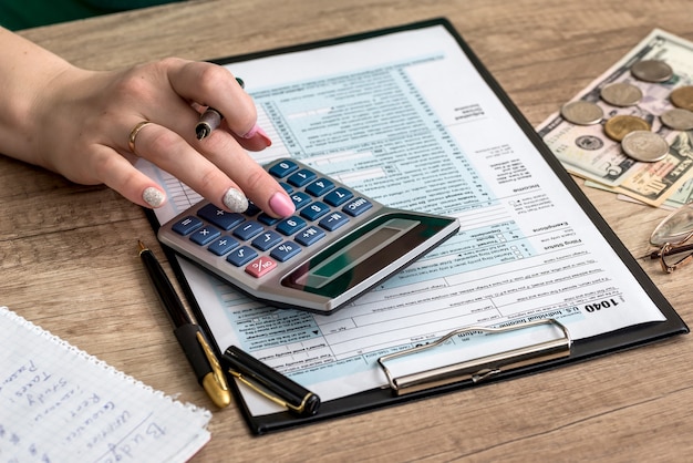 Woman filling tax form with money and calculator