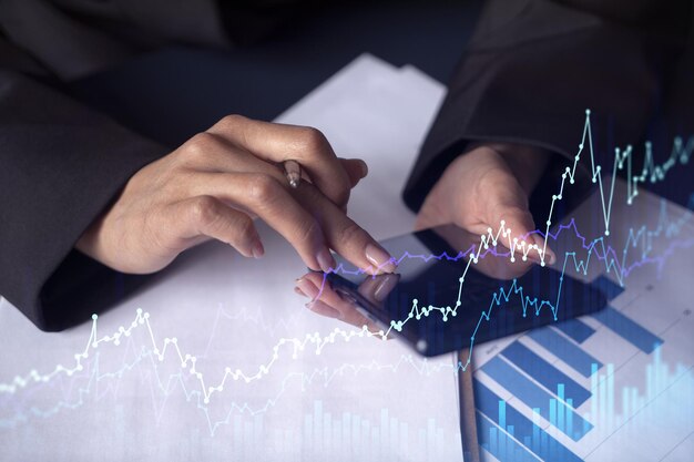 A woman financial trader in formal wear is checking the phone to sign the contract to invest money in stock market Internet trading and wealth management concept Forex hologram chart