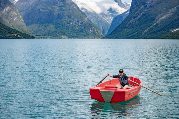 Woman fishing on a boat. Beautiful Nature Norway natural landscape. lovatnet lake Lodal valley.