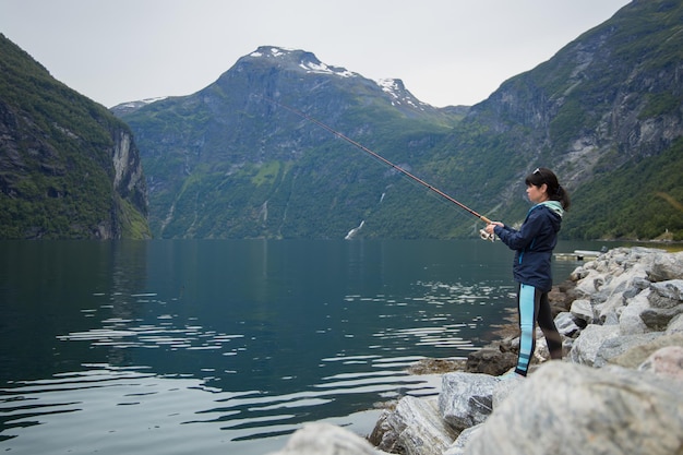 Женщина ловит рыбу на удочке, спиннинг в Норвегии
