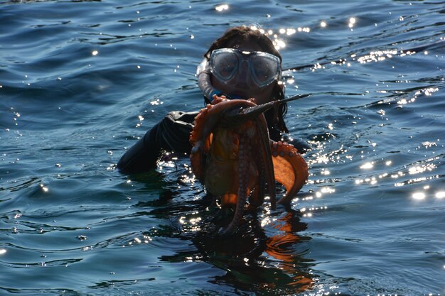 Foto donna che pesca un polpo mentre nuota in mare