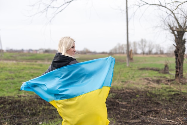 Woman flag of ukraine near burnt tree