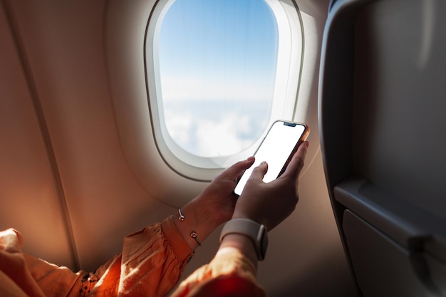 Woman flies in an airplane and holds a smartphone Travel and phone Phone mockup Girl using smartphone app