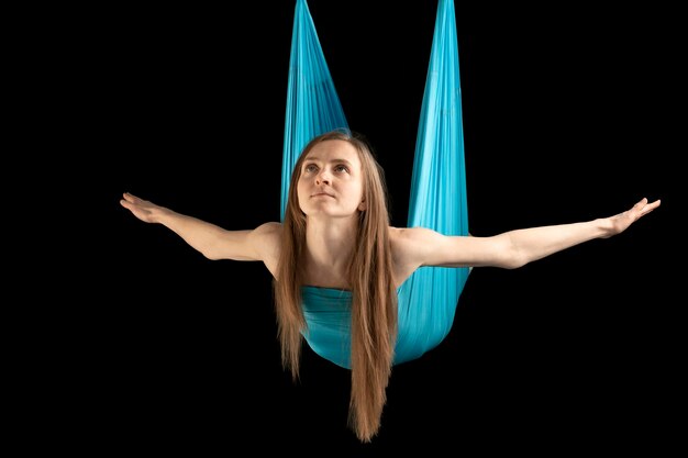 Woman flies on yoga hammock. Portrait of young woman during gymnastic training. Practicing fly yoga.