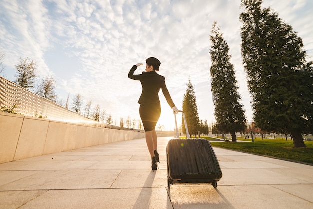 Woman in flight stewardess carries a large suitcase