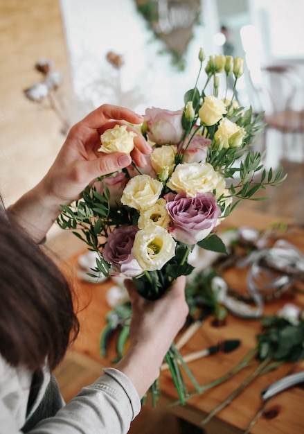 Woman florist collects bouquet decorates different flowers