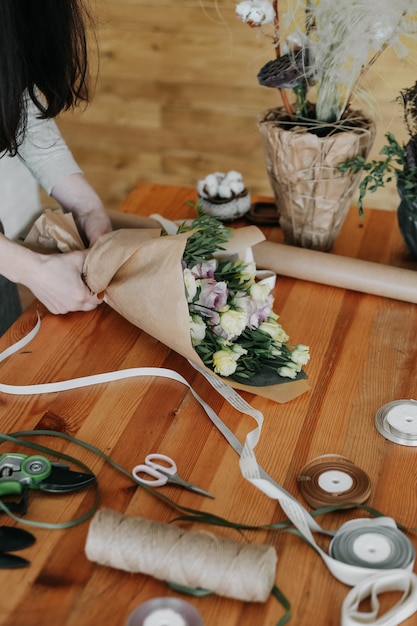 女性の花屋は異なる花を飾る花束を収集