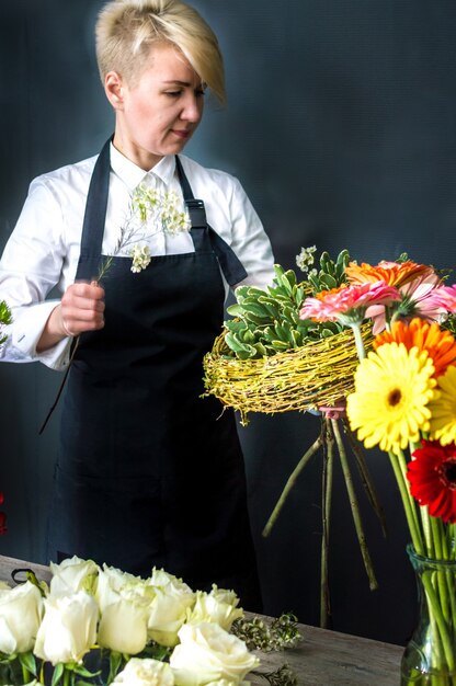 Foto fiorista della donna al negozio di fiori che prepara un mazzo di fiori. copia spazio. foto verticale