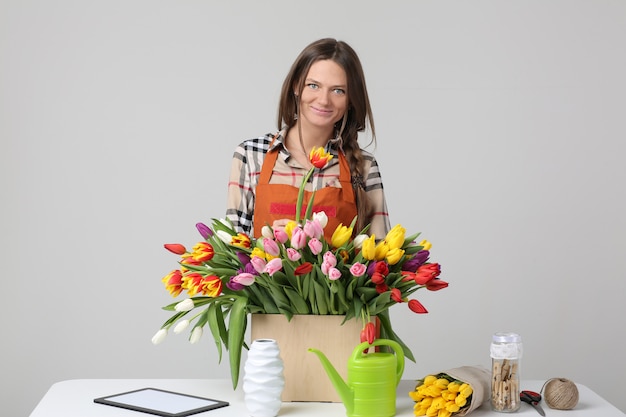 Woman florist on a gray wall with tulips