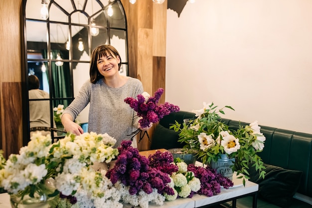 Woman florist making lilac bouquet in flower shop