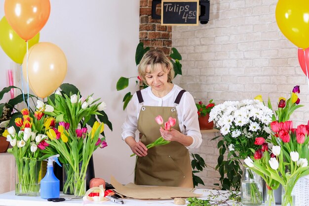 Woman florist packs a bouquet of tulips