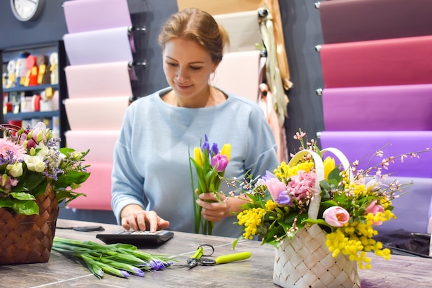 La donna in un negozio di fiori che fa fiore.
