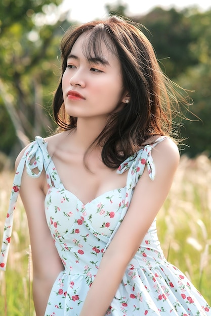 A woman in a flowered dress sits in a field