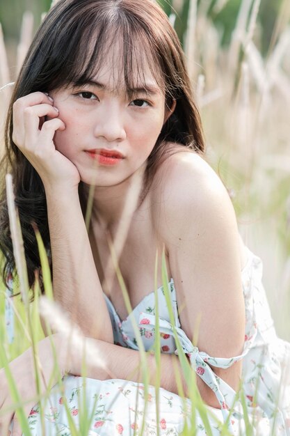 A woman in a flowered dress sits in the grass