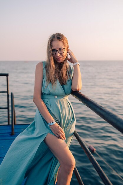 Женщина в длинном платье на приморском пирсе