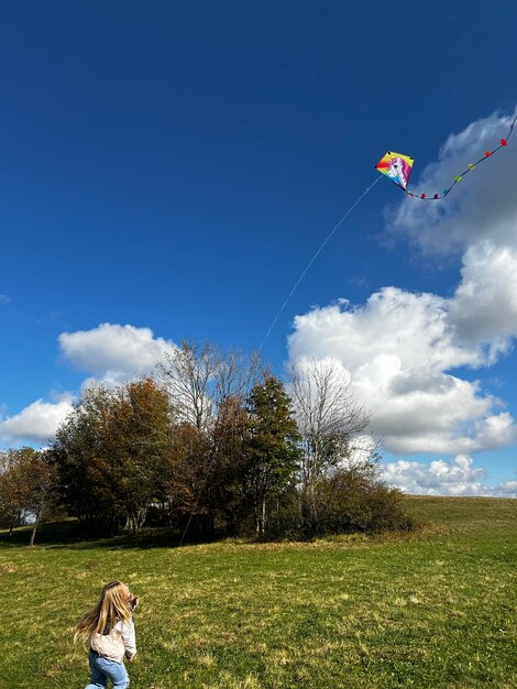 Foto donna che fa volare un aquilone sul campo contro il cielo