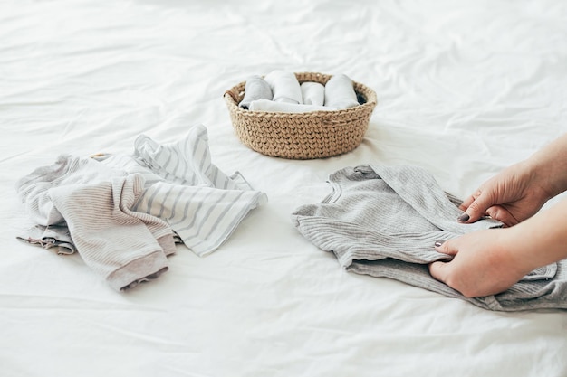 Foto donna che piega i vestiti nel cesto di iuta nel sistema konmari concetto di organizzazione dei vestiti minimalisti