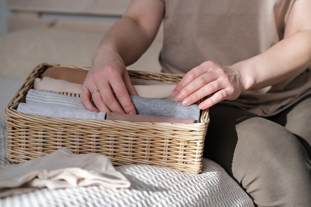 Foto una donna piega i vestiti in un contenitore di vimini concetto di stile di vita minimalista