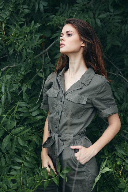 Woman in the forest The hand in the pocket of the overalls looks aside background