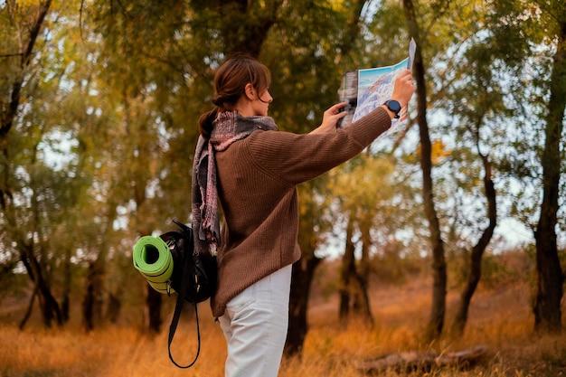 Photo a woman in the forest with a map a girl drinking tea in the forest a topographic map in her hands