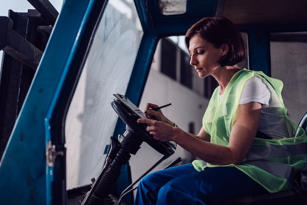 Woman forklift operator signing document in the vehicle