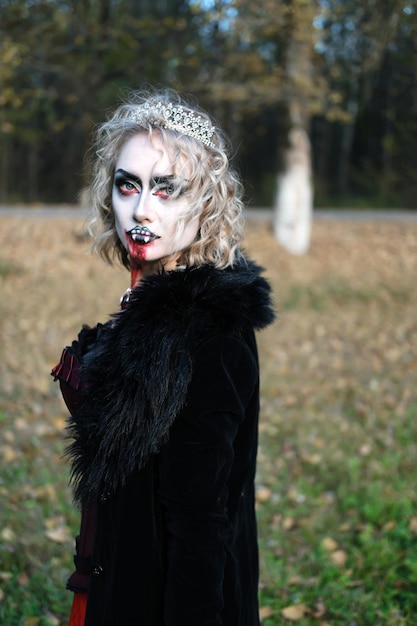 A woman in the form of a vampire or witch with white makeup on her face